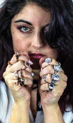 Attractive woman with blue eyes with a lot of different rings in her hands. Portrait of white woman with jewels and precious stones.