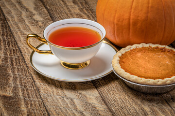cup of hot tea and pumpkin pie on a rustic wood, Thanksgiving and fall holidays concept