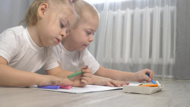 happy family brother and sister teamwork concept. little boy and girl draw on floor in a sketchbook lifestyle. brother and sister in the room draw with crayons