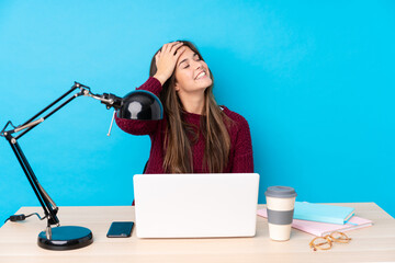 Teenager Brazilian girl with a laptop in a table laughing