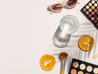 Beauty desk top view with cosmetics, palm shadows and copy space