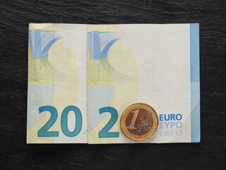 2021 sign made from 20 euro bank note and one euro coin with Christmas balls decorations on a dark background.