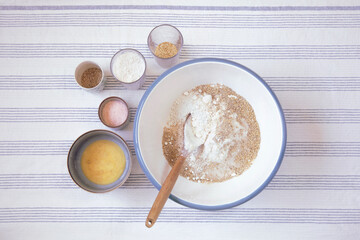 Preparing dough for bread  in the kitchen. Bowl with flour and ingredients for recipe on the side, flat lay. Baking at home.