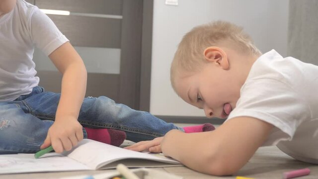 happy family a brother and sister teamwork concept. little boy and girl draw on floor in sketchbook lifestyle . brother and sister in the room draw with crayons