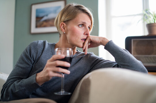 Depressed woman with wine indoors at home, mental health and alcohol addiction concept.