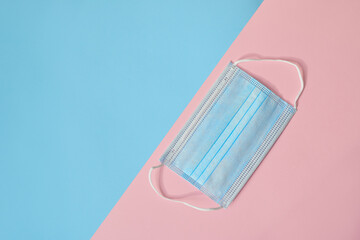 Medical disposable protective mask on a pink and blue background. The concept of protecting health from the virus. Copy space, top view
