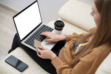 Beautiful girl holding gold credit card in hands and using laptop computer to perform shopping online by inputting card information for payment method. Ecommerce business concept.