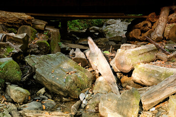 Fototapeta na wymiar Large stones under a wooden bridge in the summer forest, Sochi, Russia. Bottom view of large boulders.