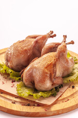 Fried quail on a wooden cutting board isolated on a white background.