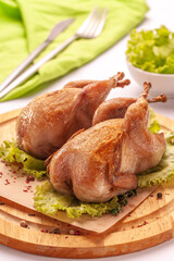 Fried quail on a wooden cutting board isolated on a white background.