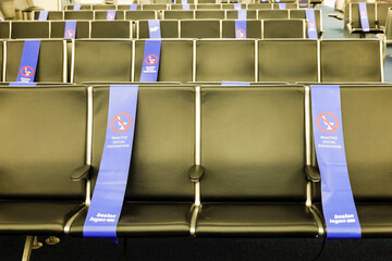 Boston Massachusetts, USA Seats in the departure terminal at Loga aiport with social distance ribbons to prevent contact. - obrazy, fototapety, plakaty