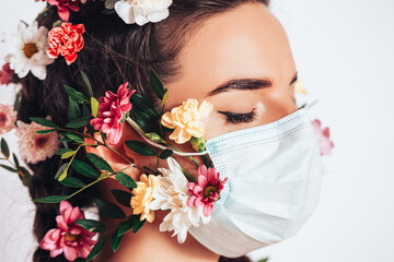 Beautiful nymph woman in a medical mask on a white background, in her hair she has flowers and a wreath of flowers