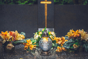 a candle and orange flowers on the tomb on All Saints Day