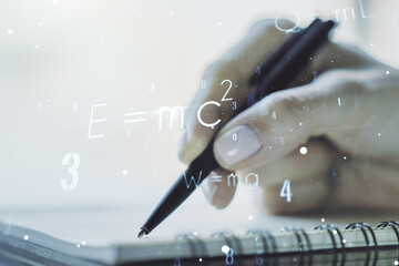 Creative scientific formula hologram with woman hand writing in notepad on background, research concept. Multiexposure