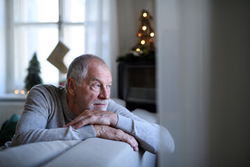 Lonely senior man sitting on sofa indoors at Christmas, solitude concept. © Halfpoint