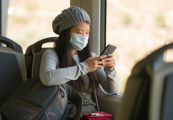 new normal traveling - young attractive and pretty Asian Chinese woman in face mask sitting on...