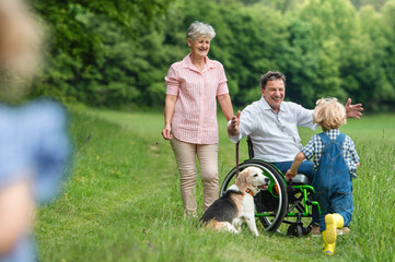 Small children with senior grandparents and dog on a walk on meadow in nature.