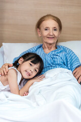 Asian Lovely girl visit and encourage grandmother on patient bed in hospital