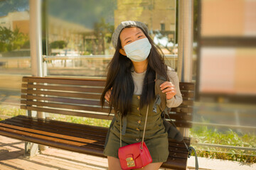 young beautiful and happy tourist Asian woman traveling during new normal - attractive Japanese girl with backpack waiting for train at station platform doing tourism while virus