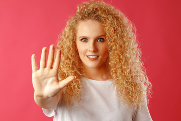 Confident young blonde woman looking at camera and gesturing 'stop'