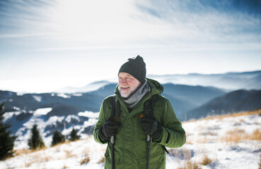 Fototapeta na wymiar Portrait of senior man standing in snow-covered winter nature.