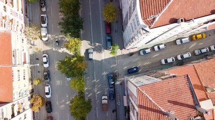 Aerial view of the city traffics at the center. Vehicles are moving on the road between buildings.