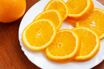 Fototapeta na wymiar Slices of ripe orange on a white plate on the table