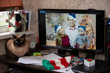 On the computer monitor, a family with a small child via video link. Stay at home, quarantine and social distancing on New Years.