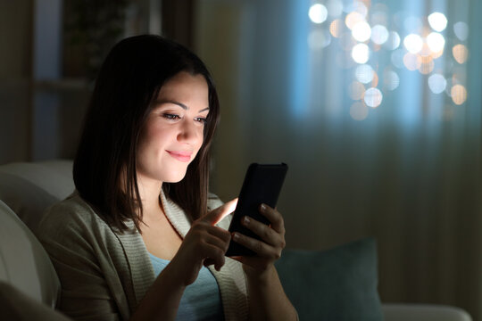 Woman checking cell phone in the night at home