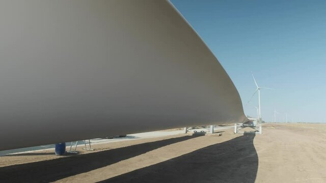 Huge wind turbine blade on the ground. Preparation for mounting the HTG blade. Wind farm. Wind power plant.