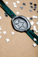 Vintage paper gift with wax seal stamp wrapped in ribbon and primped with silver stars.