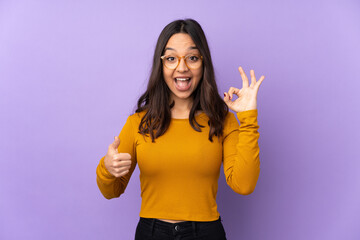 Young mixed race woman isolated on purple background showing ok sign and thumb up gesture