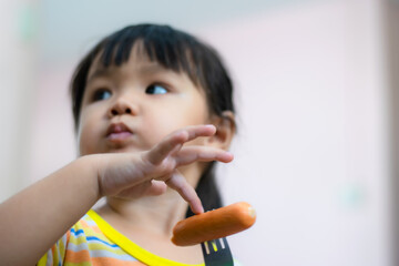 A 3-year-old Asian girl eating hot dog.