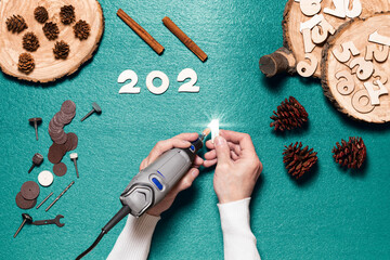 The master uses an electric engraver and wood carving tools to make wooden attributes for the celebration of Christmas and New year - the numbers that make up the date of the New year 2021.