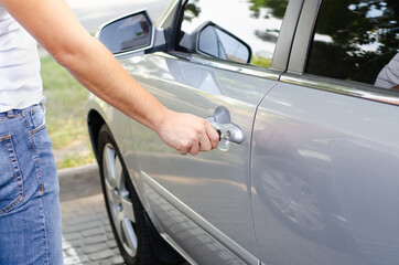 Male hand inserting a key into the door lock of a car