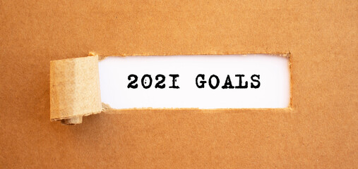 Text 2021 GOALS appearing behind torn brown paper.
