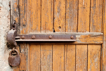 Rusty iron lock on a old wooden door with peeled yellow paint abstract background.