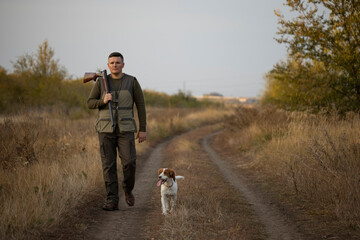 Hunter with Russian spaniel dog walking on the dirt road. Image taken during big game hunting trip....