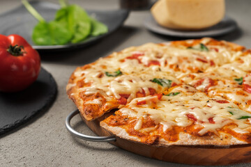 Pizza with cheese and vegetables near tomatoes and greens