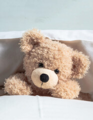 Kids bedtime. Cute teddy playing with pillows in bed,