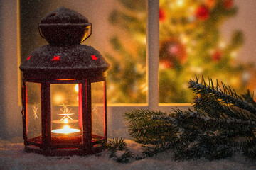 Red lantern on a widowsill covered in snow on a snowing night. A Christmas tree inside the house in...