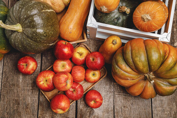 Pumpkins and red apples on wooden background