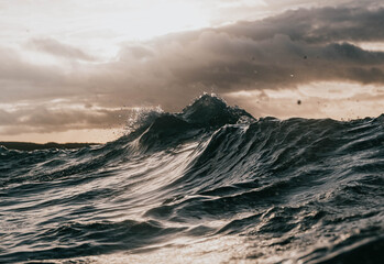 moody waves crash with sun breaking through - obrazy, fototapety, plakaty