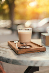 Coffee with milk drink on a wooden tray on a street table in the park