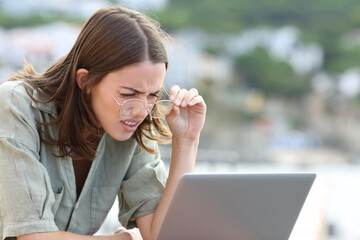 Woman forcing sight wearing eyeglasees reading laptop