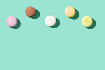 Assorted macaroons on bright blue green colored background, colorful french cookies macarons.