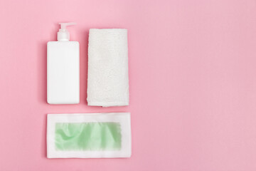 Set of female of hair removal. Wax strips, body moisturizer and white cotton towel on pink paper background with copy space. Top view.