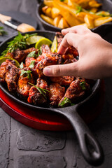 Hand swiping roasted chicken wings in barbecue sauce with lime