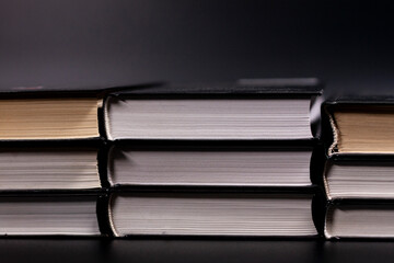 Neat stacks of books. Dark background. Side view.