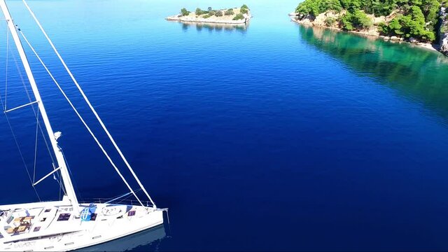 Aerial view of Siderona bay, Corinthia, Greece, on a lovely bright day in a calm blue and turquoise sea, with sailing boat